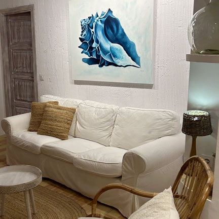 sofa blanco con cuadro de caracola azul